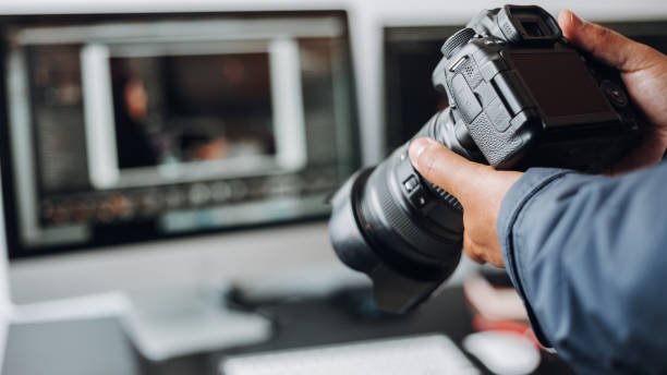 photographer hand camera and computer on desk